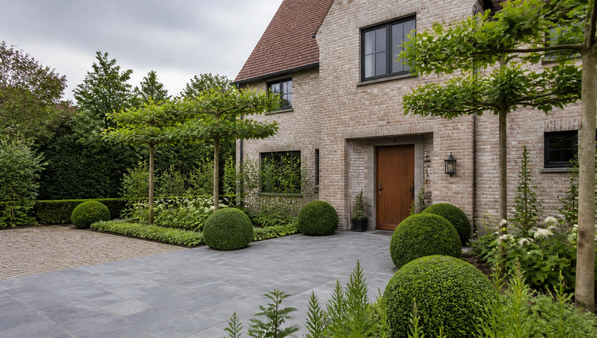 Entrée pavée avec buis taillés et arbres palissés